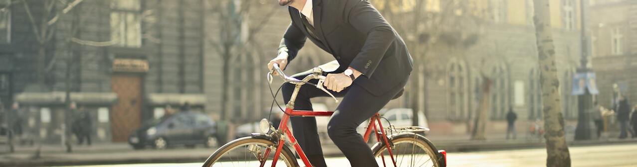 man-in-black-suit-riding-bicycle-down-the-street-1843752